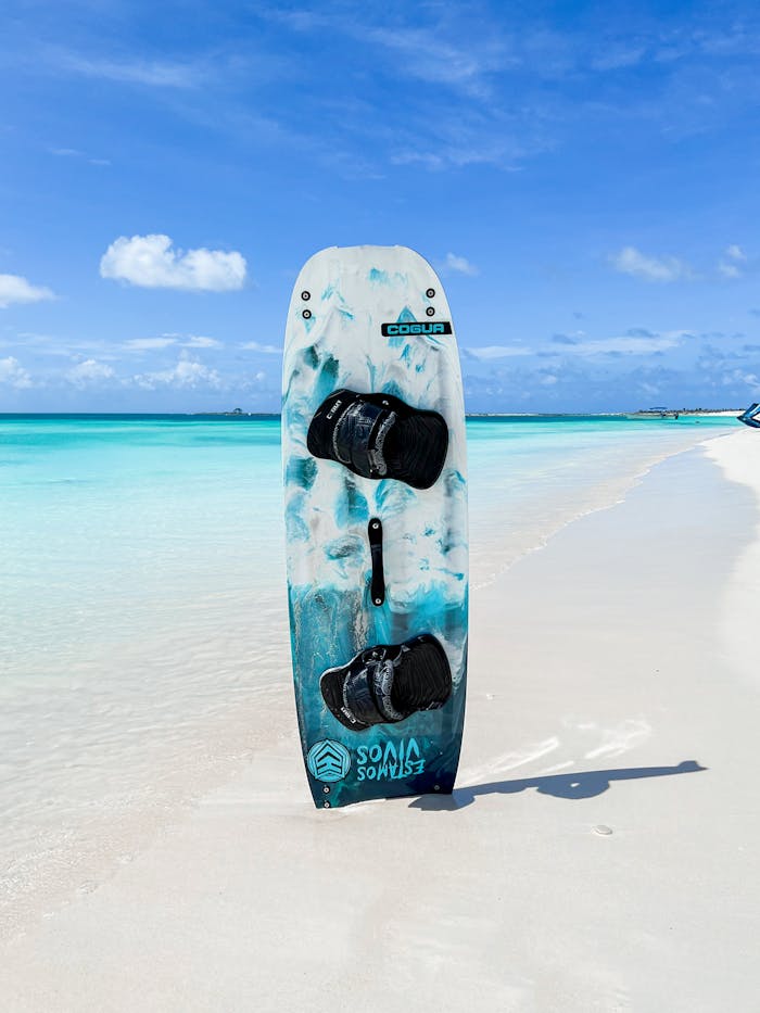 mobile-02 A colorful kiteboard stands on a pristine Venezuelan beach under a blue sky.