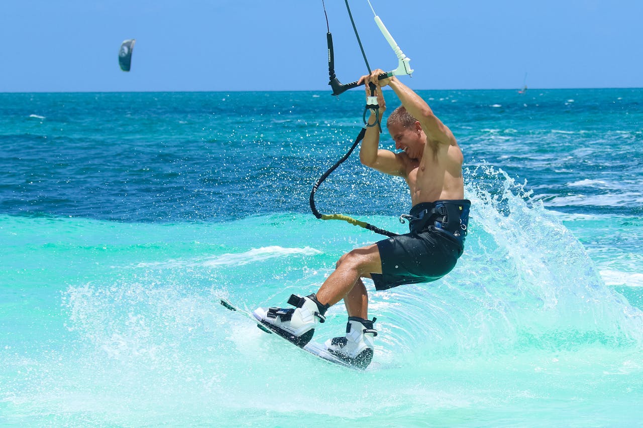 our-story Man enjoying an exhilarating kiteboarding experience in the vibrant turquoise ocean on a sunny day.