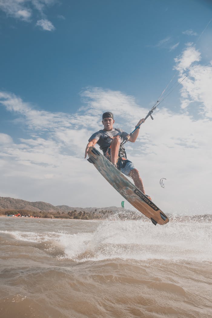digital-01 Young man kitesurfing midair over the sea on a sunny day, showcasing thrilling water sport action.