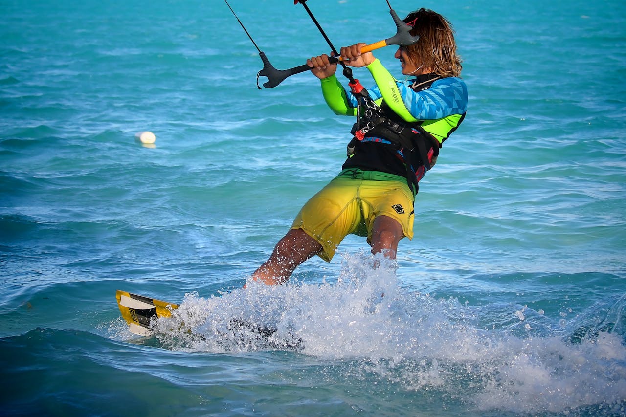 creative-01 Experience the thrill of kitesurfing as a man rides the waves on a sunny day.
