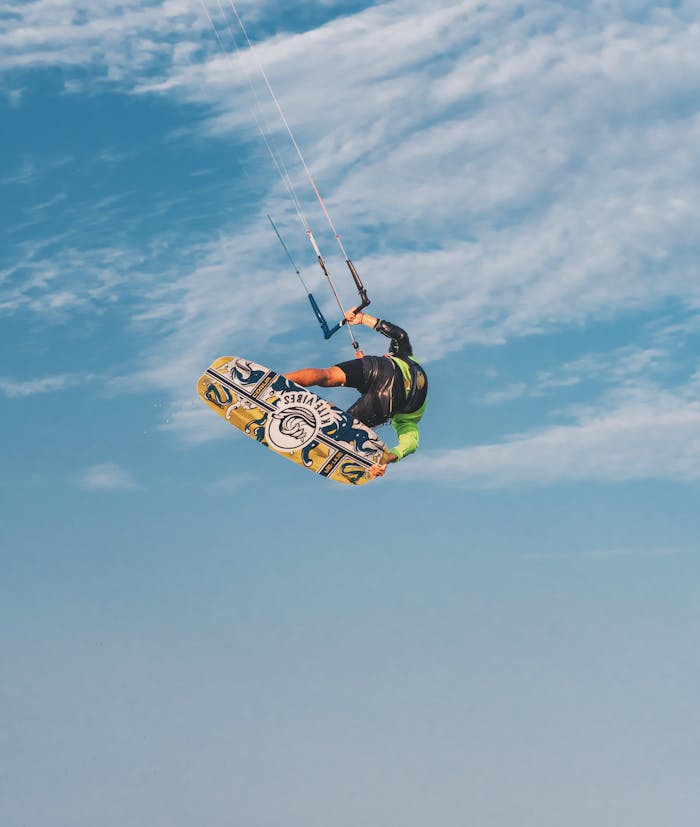 creative-03 Capture of an adventurous kiteboarder showcasing a thrilling midair trick against a clear blue sky.