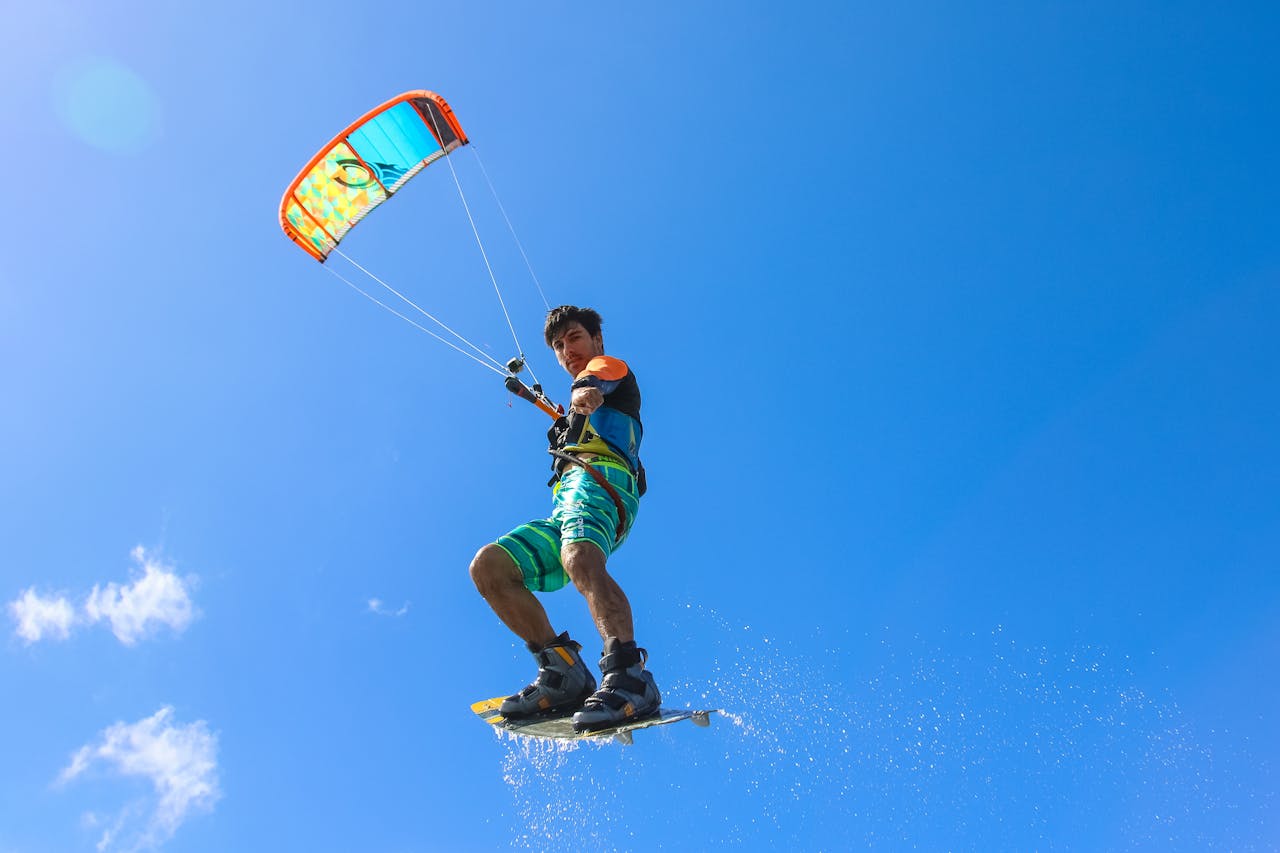 Services-01 A thrilling kiteboarder performing stunts in the air with clear blue sky backdrop, capturing the essence of adventure and sport.