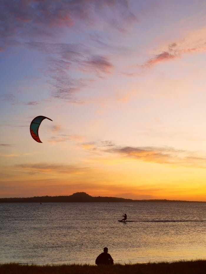creative-03 A breathtaking scene of kitesurfing at sunset on a serene sea in Cuyo, Philippines.